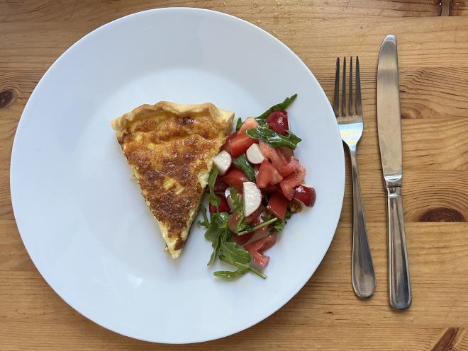 Ein Stück herzhafter Käsekuchen mit Salat.